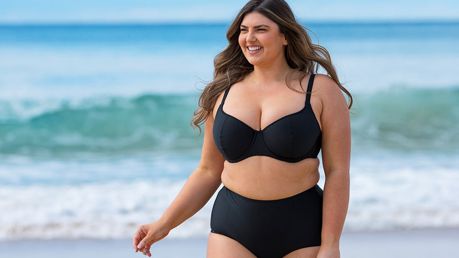 Brunette model wears black underwire bikini top and high waisted pant