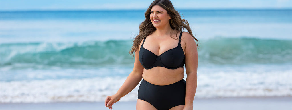 Brunette model wears black underwire bikini top and high waisted pant