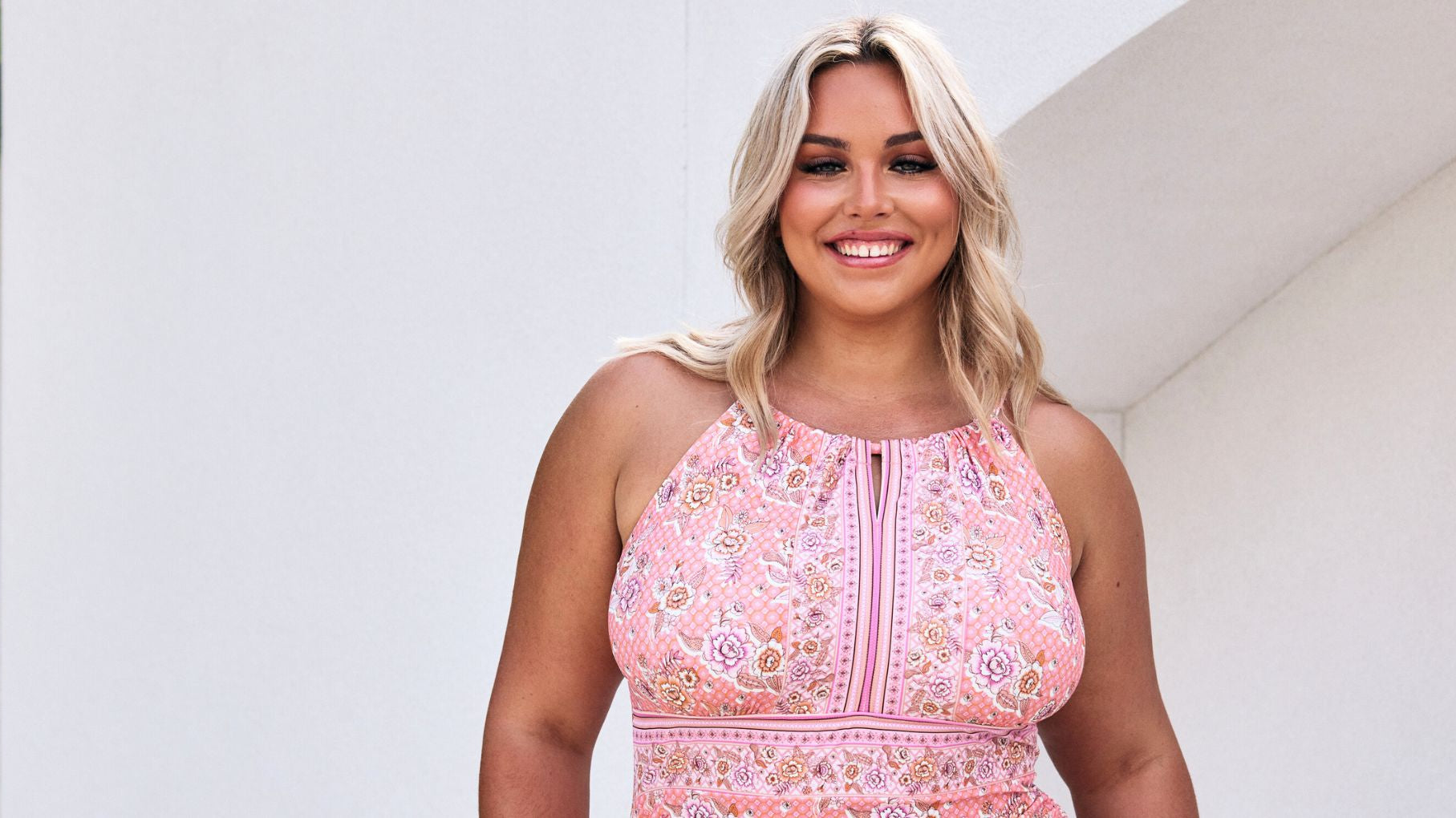 Woman with blonde hair wears pink floral high neck swimsuit