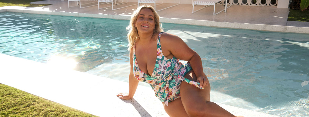 Woman with blonde hair wears tropical print plunging neckline one piece swimsuit
