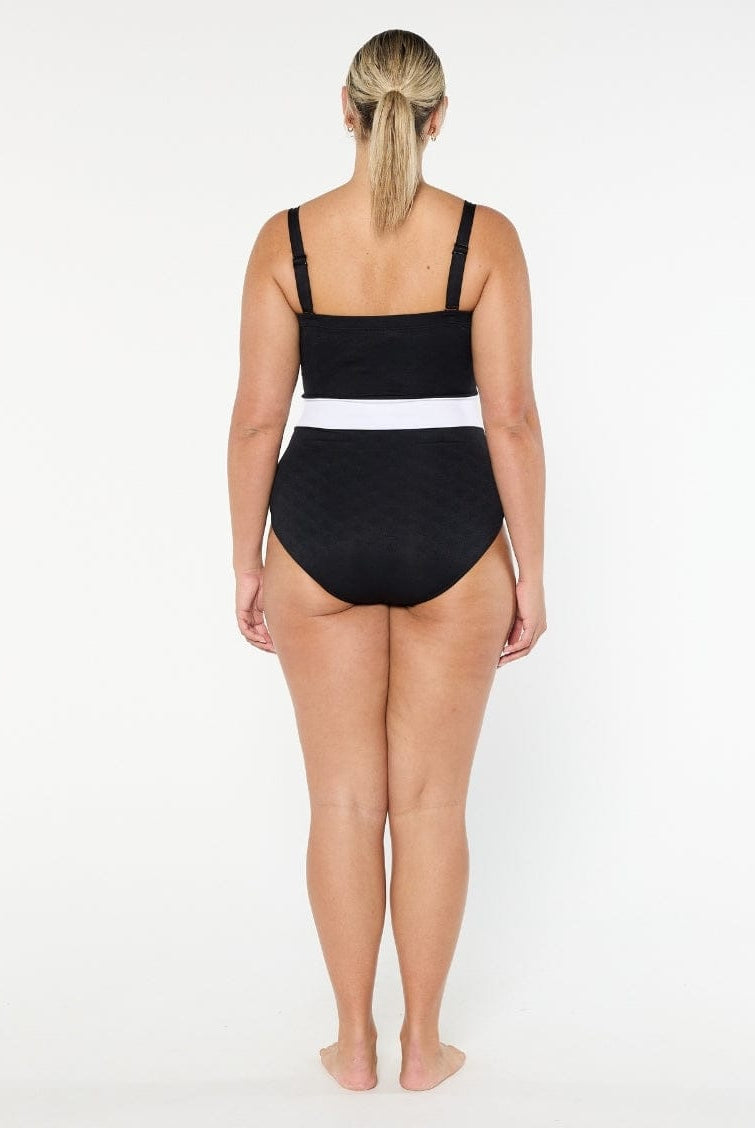Woman wearing a black swimsuit with white trim on a white background