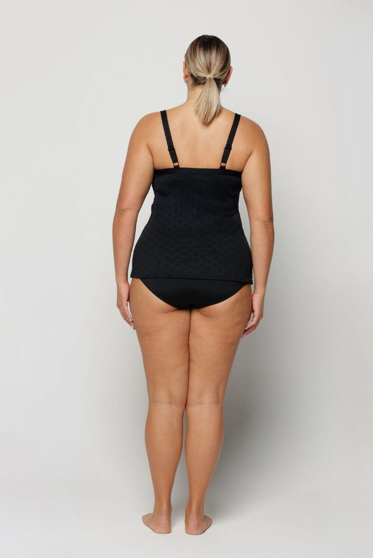 Woman wearing a black swimsuit on a plain background