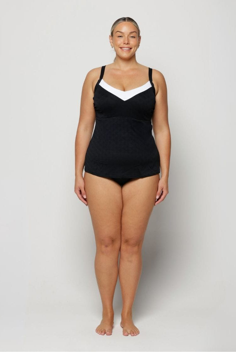 Woman wearing a black swimsuit with white accents on a plain background