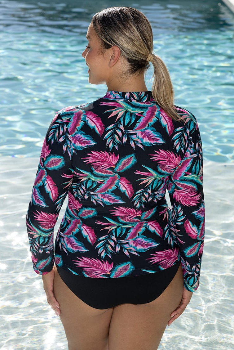 Woman wearing a colorful leaf-patterned rash guard by a pool.