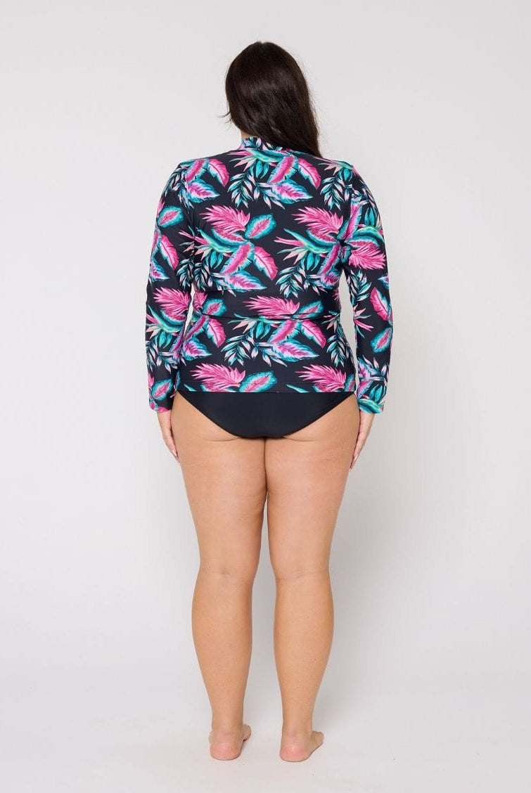 Person wearing a colorful tropical print long-sleeve shirt over a black swimsuit on a white background