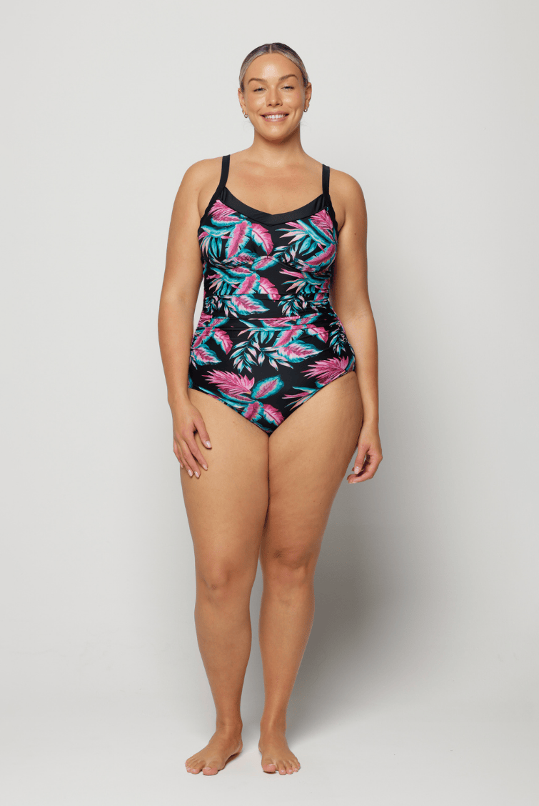 Woman wearing a tropical leaf patterned swimsuit on a plain background