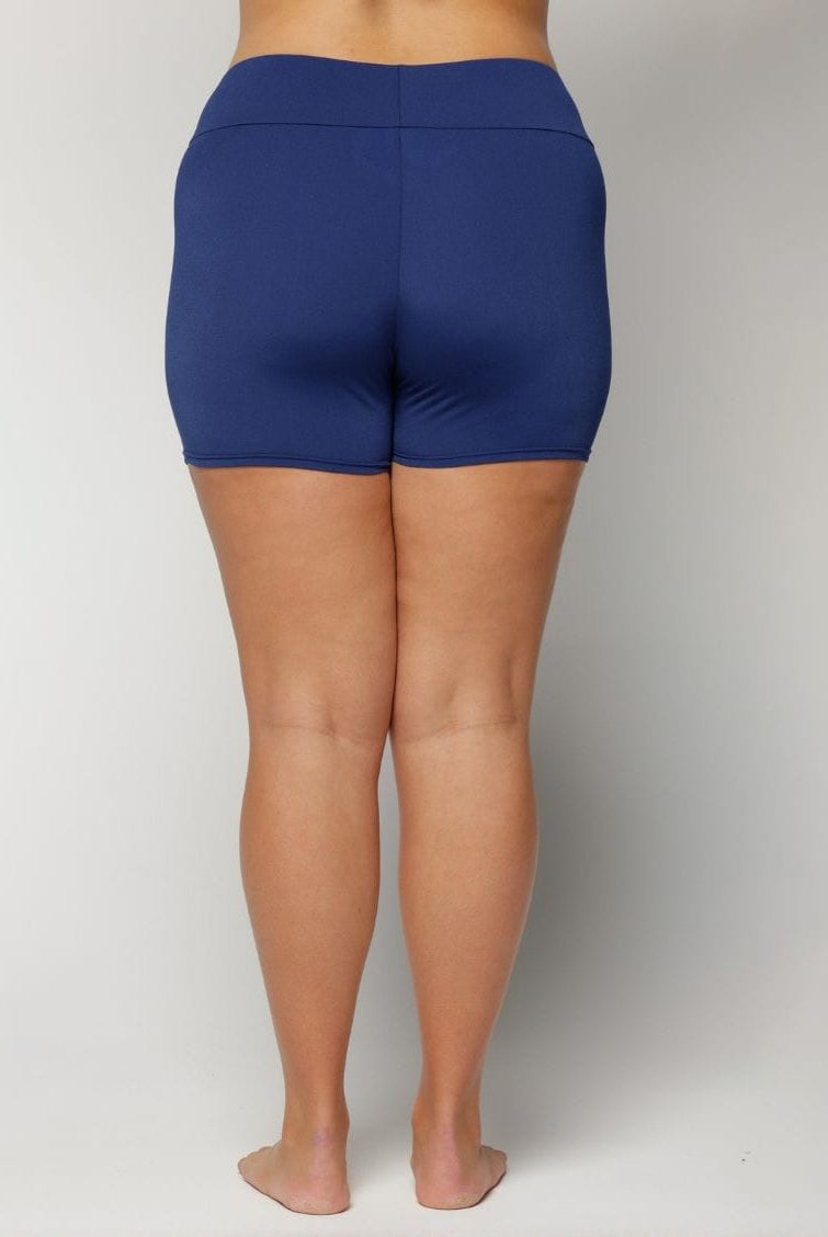 Person wearing chlorine resistant blue shorts on a plain background