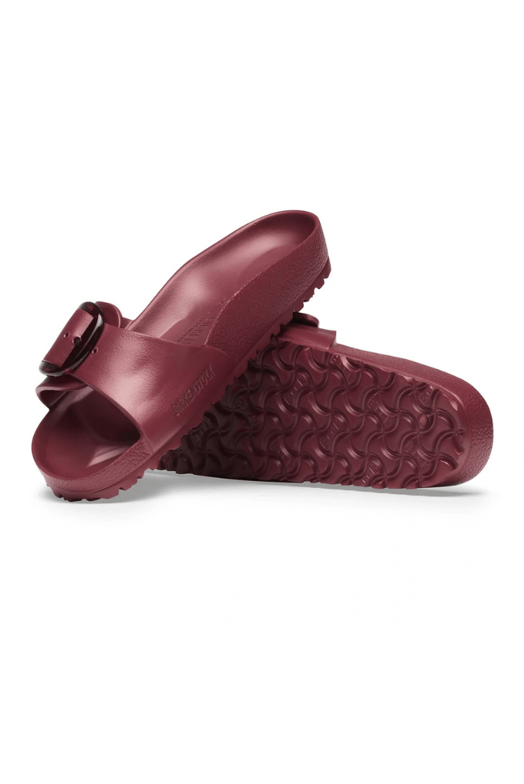 A pair of burgundy molded slide sandals with a single strap and a buckle closure, shown on a clean white background.