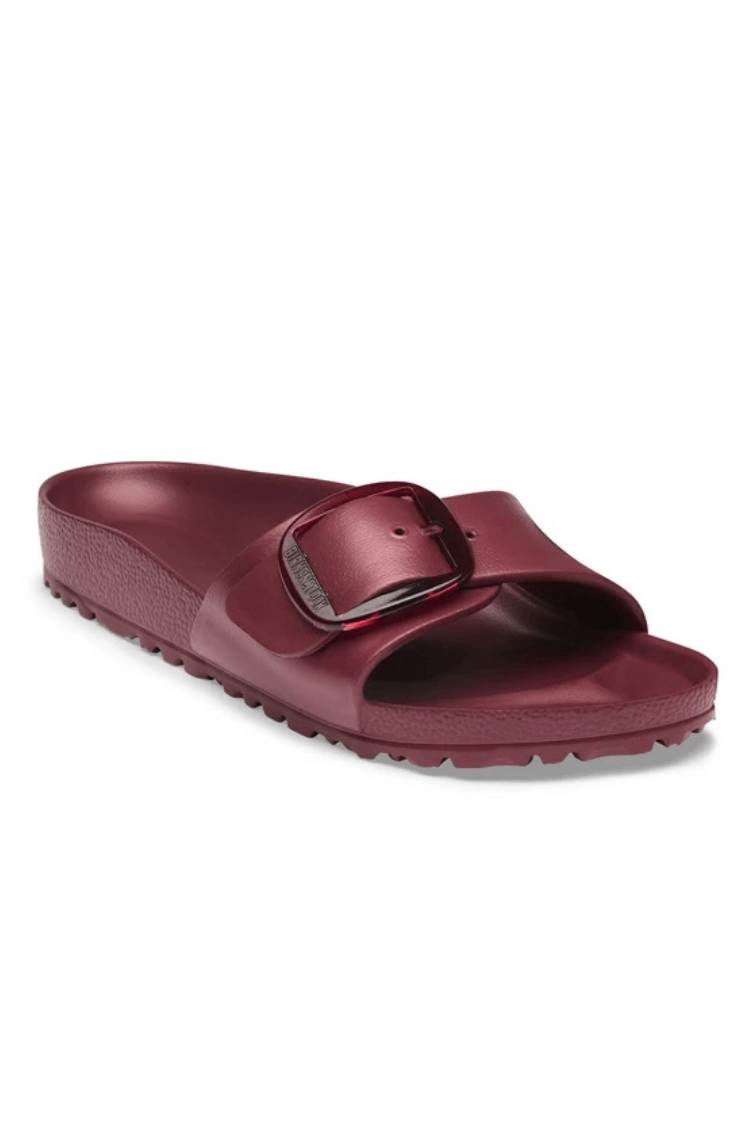 A single burgundy slide sandal with a wide strap and a metallic buckle detail, shown from a three-quarters angle on a white background.