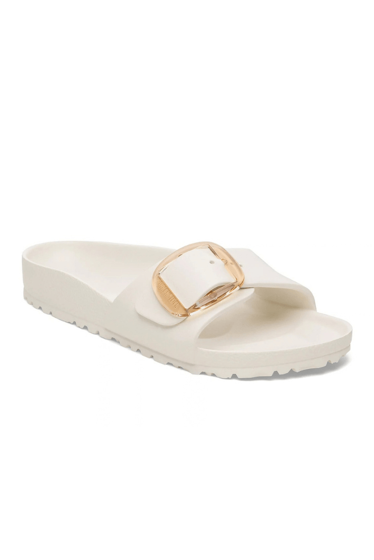 A single cream-colored slide sandal with a wide strap featuring a square gold-tone metal buckle, set against a plain white background.