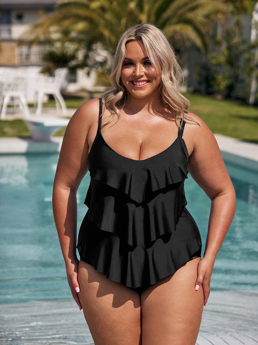 Woman wearing a black ruffled swimsuit by a pool