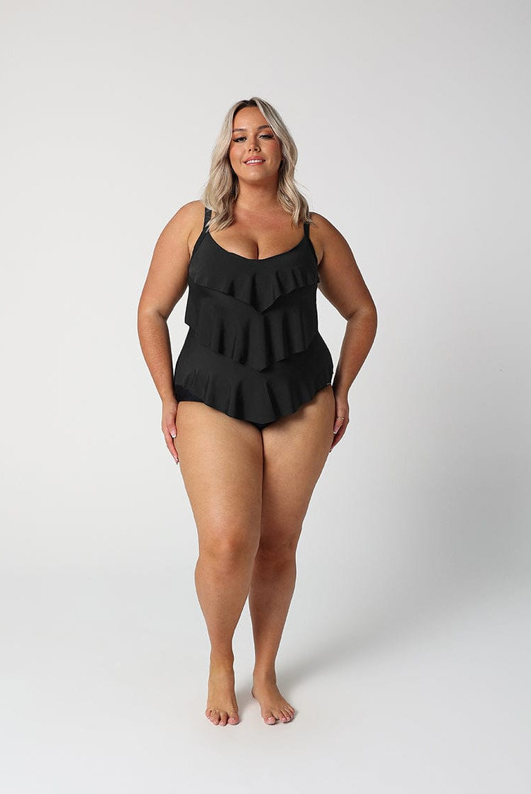 Woman wearing a black ruffled swimsuit on a white background
