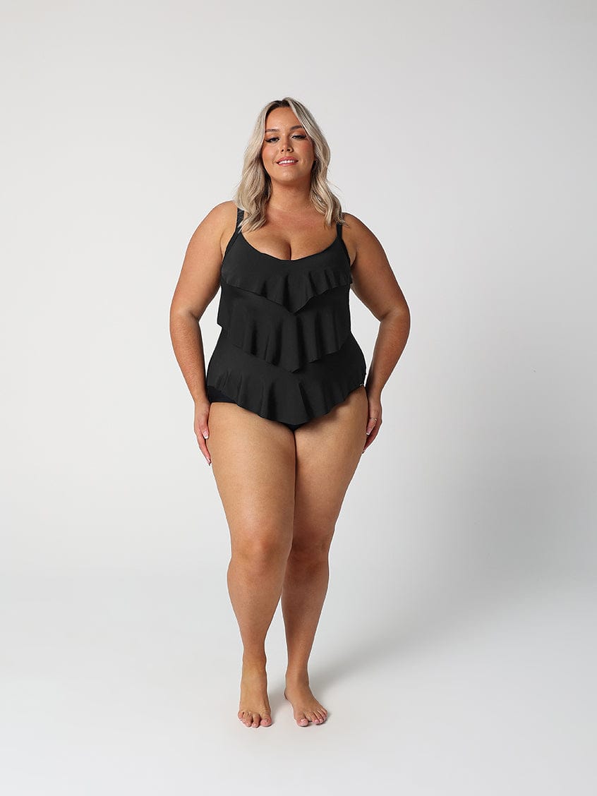 Woman wearing a black ruffled swimsuit on a white background