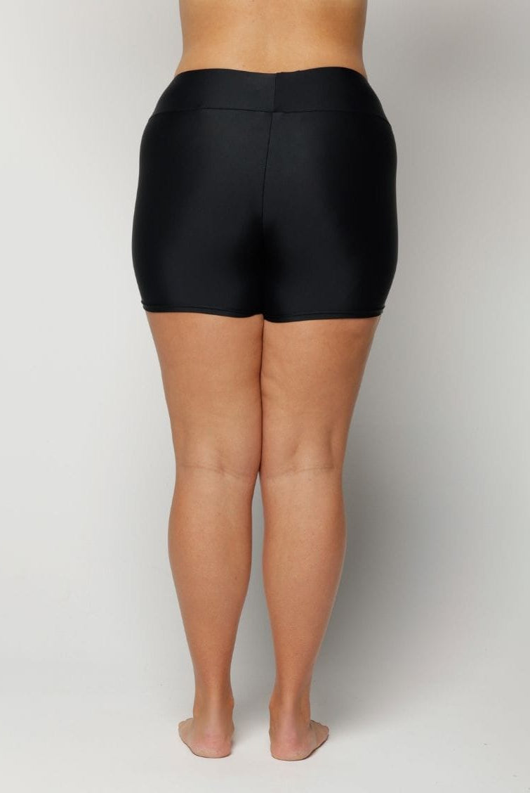 Woman wearing black shorts on a plain background