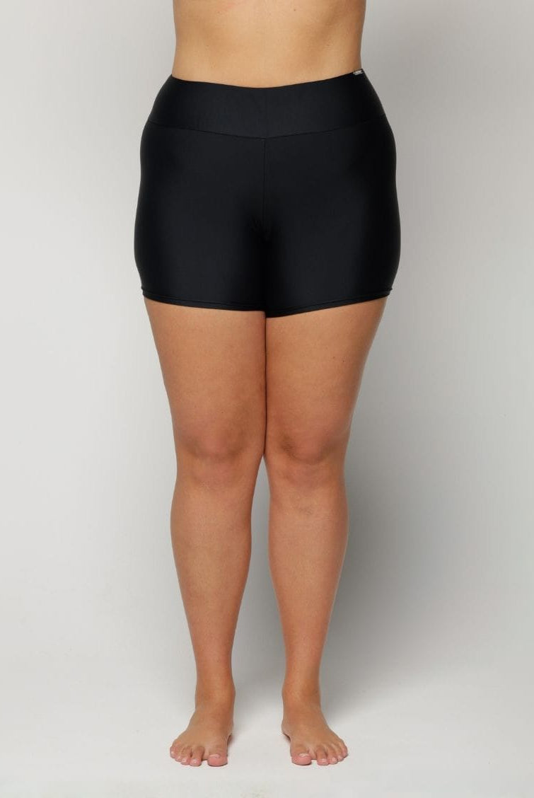 Woman wearing black high-waisted shorts on a plain background