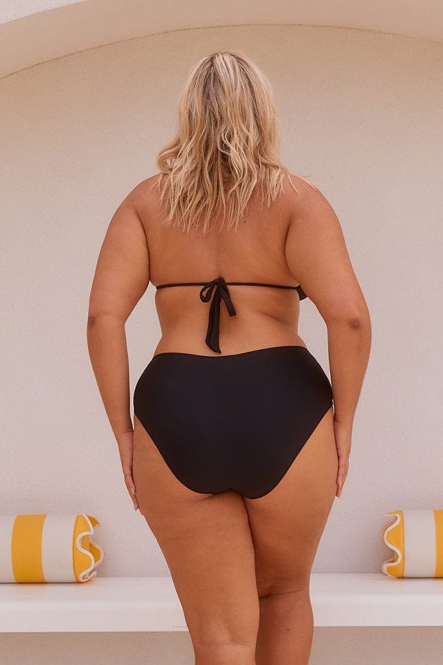 Model showing back of high rise black bikini bottoms with mid coverage