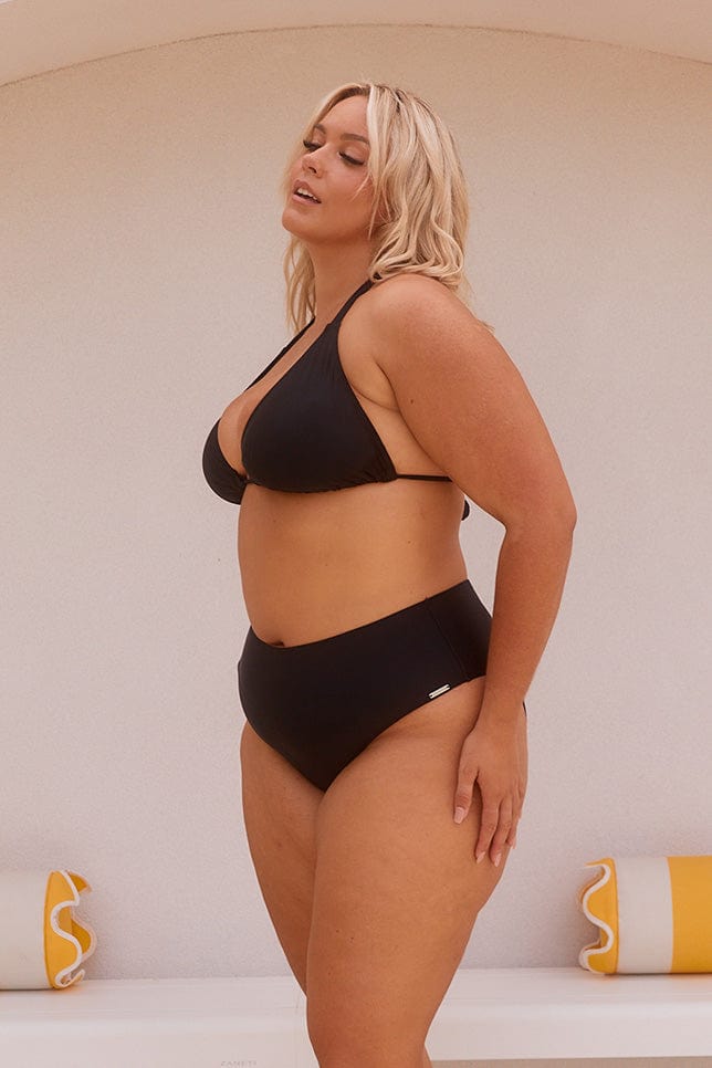 Blonde model showing side of high rise black bikini bottoms