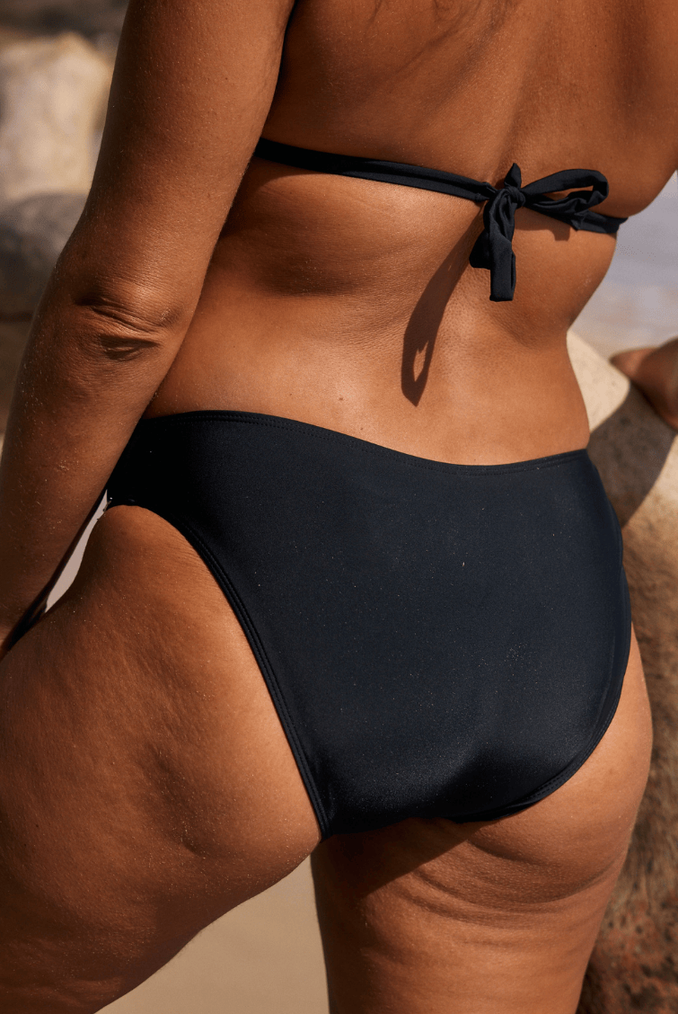 Person wearing a black bikini bottom on a beach