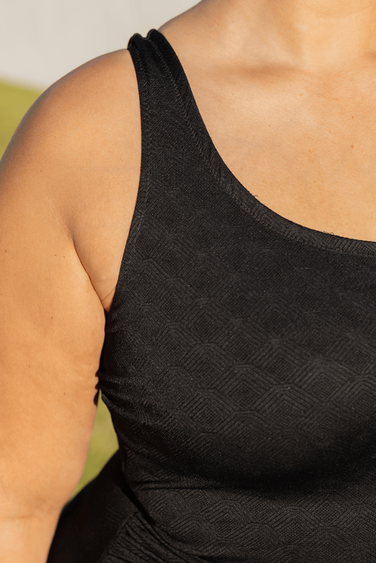 Black tank top worn by a person with a blurred background