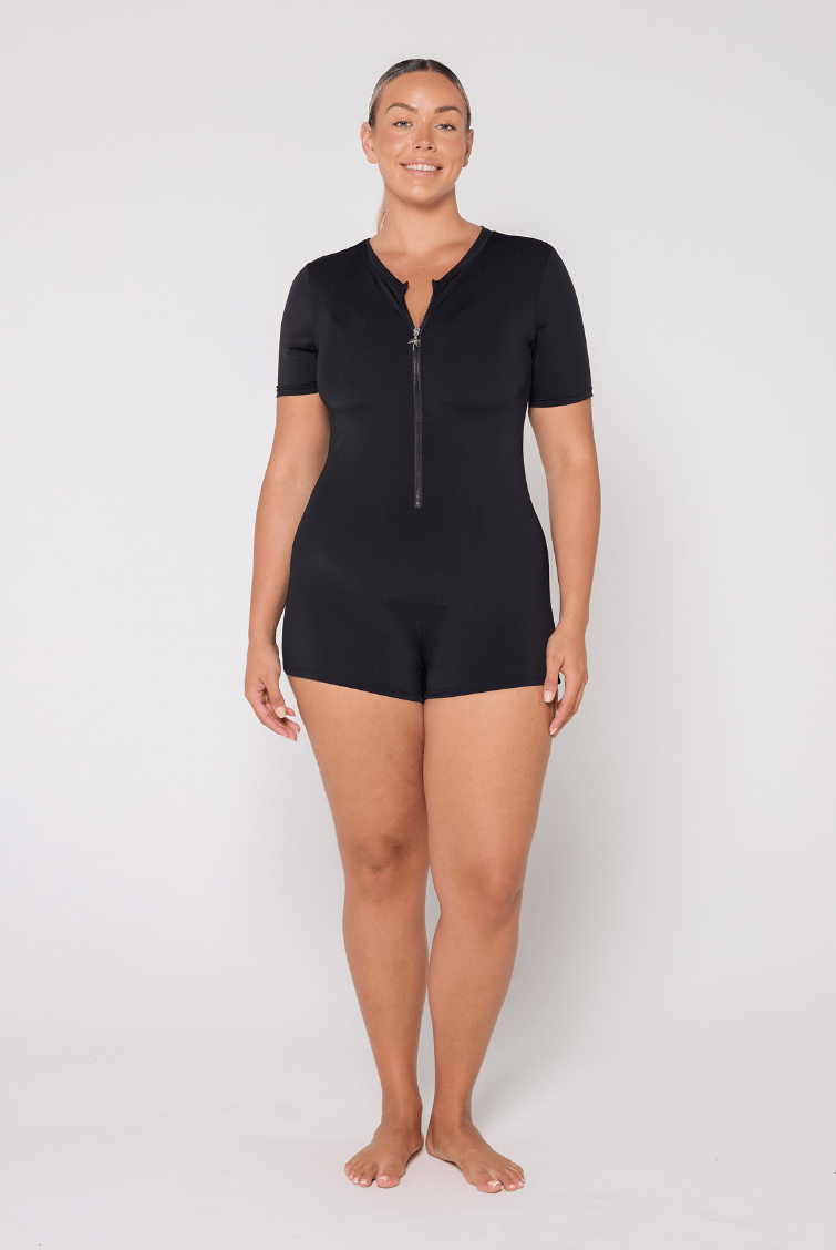 Person wearing a black zip-up jumpsuit on a white background