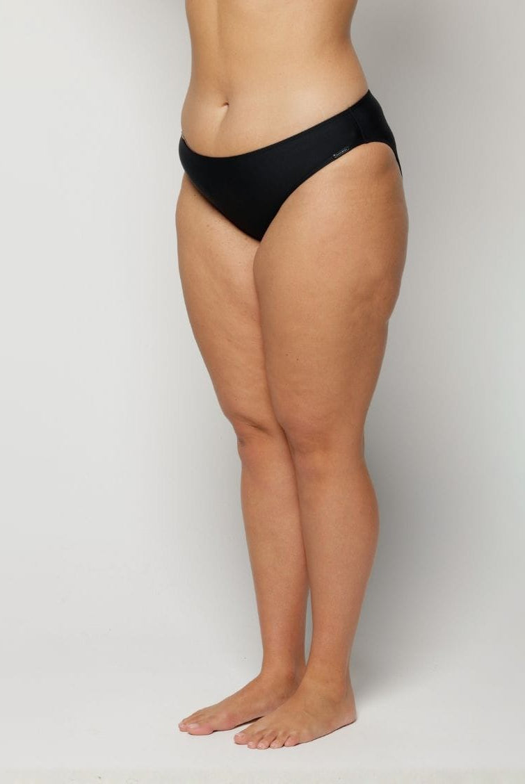 Woman wearing black underwear on a plain background
