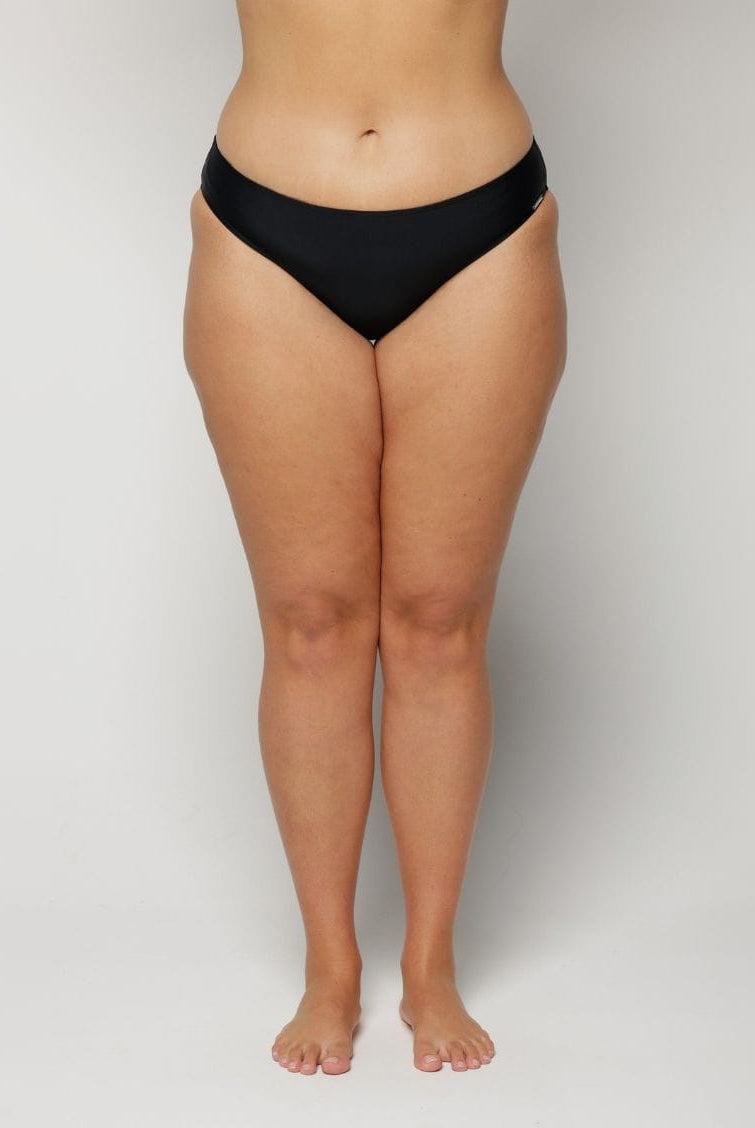 Woman wearing black underwear on a plain background