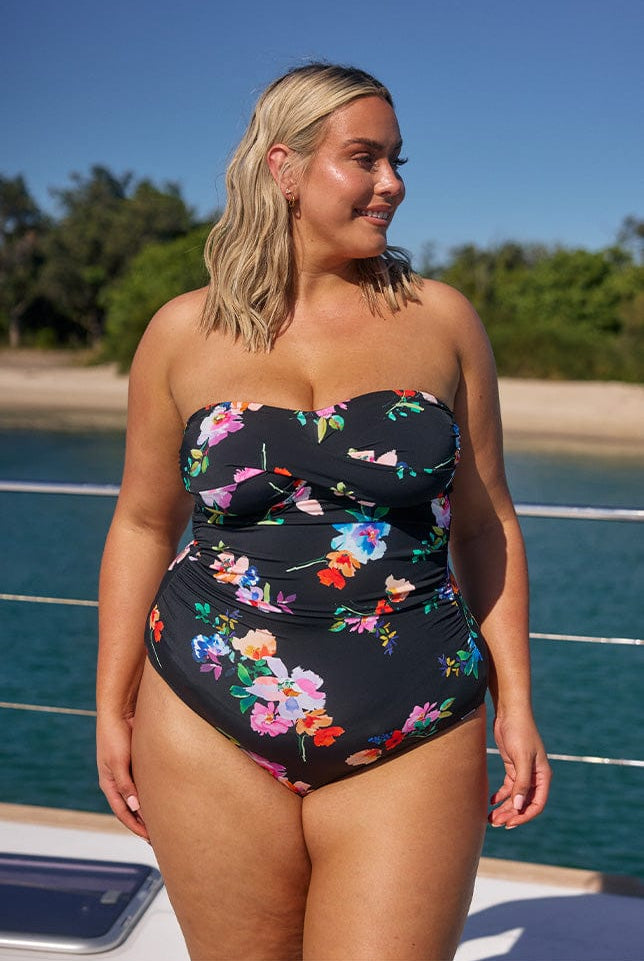 Model wearing black floral strapless one piece on boat