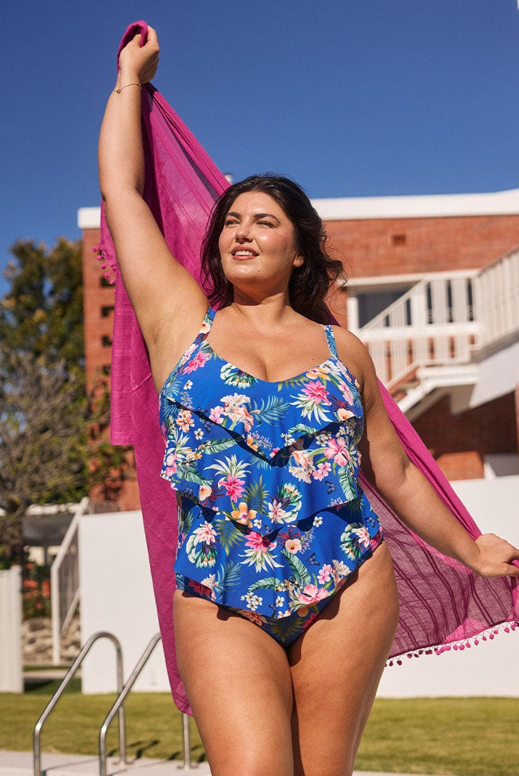 Brunette model wears tummy control one piece with 3 tier design in blue floral fabric