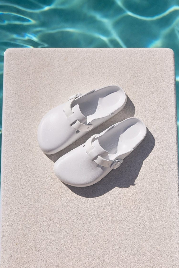 White shoes on a diving board by a pool