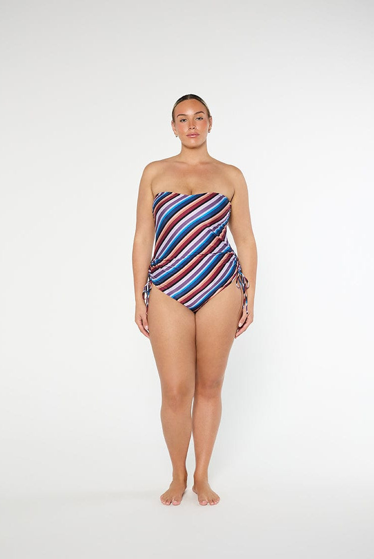 Woman wearing a strapless, multicolored striped swimsuit on a white background