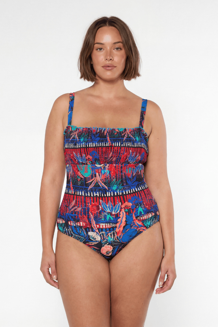 Woman wearing a colorful patterned swimsuit on a white background