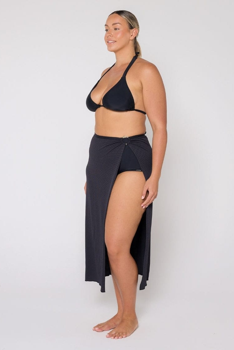Woman wearing a black bikini with a matching skirt on a white background
