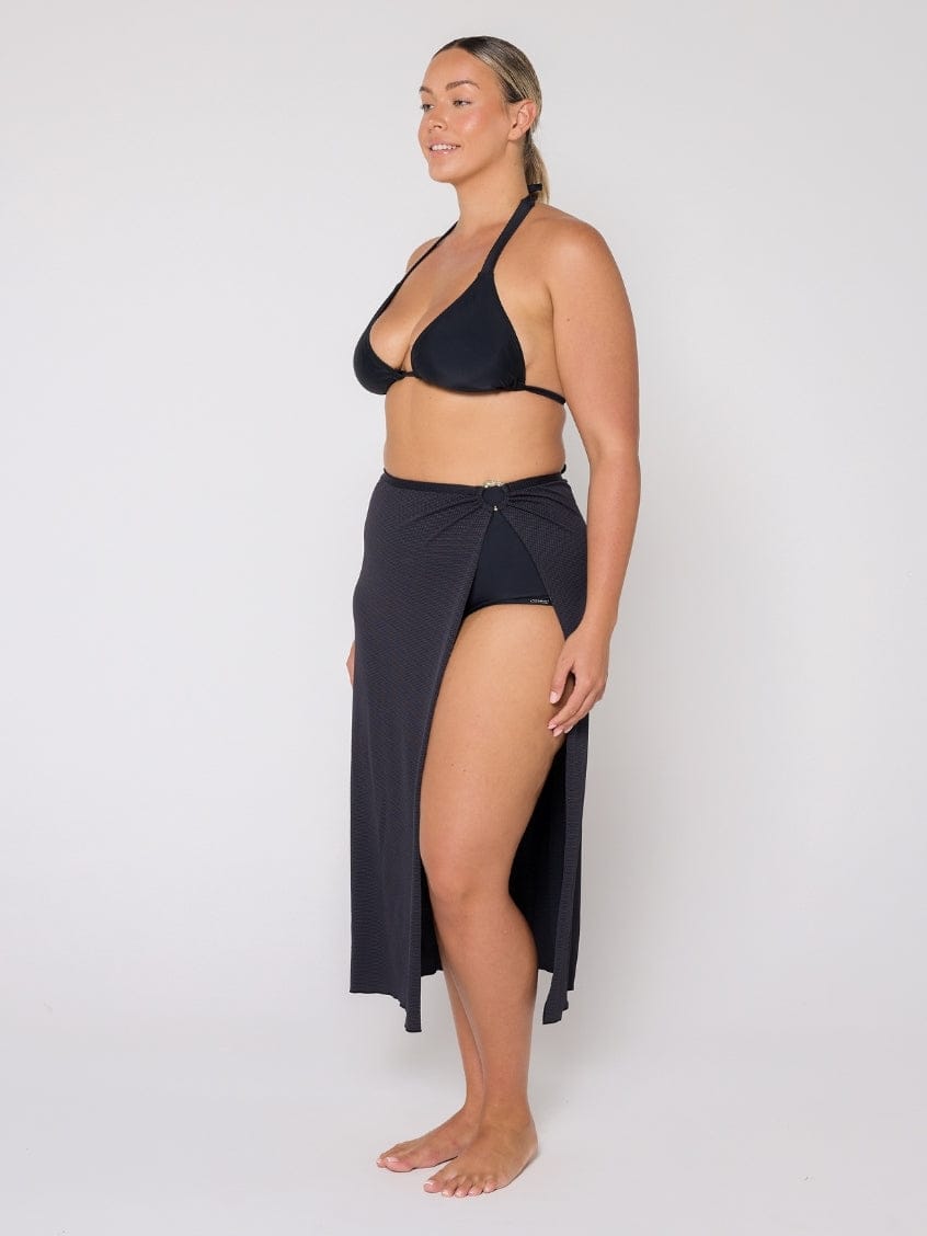 Woman wearing a black bikini with a matching skirt on a white background