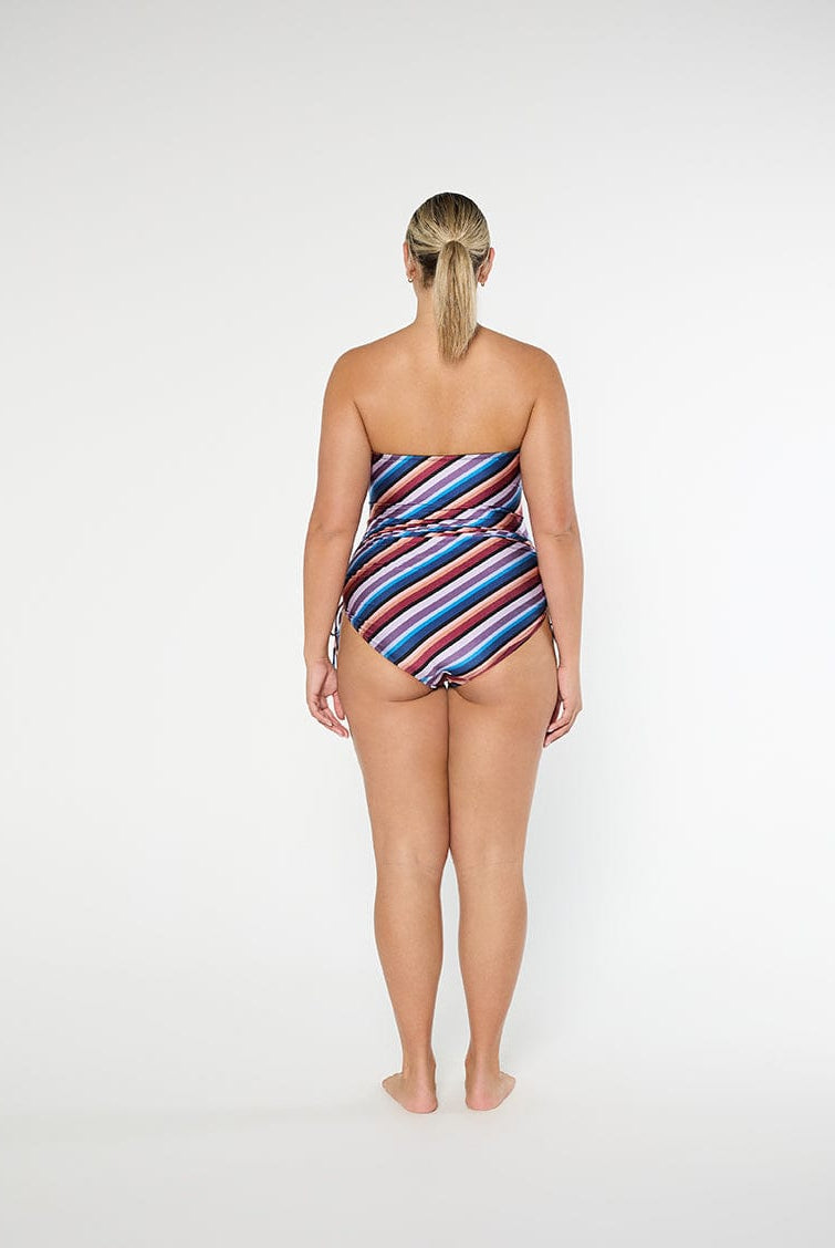 Woman wearing a strapless, multicolored striped swimsuit on a white background