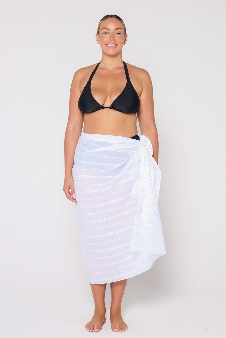 Woman wearing a black bikini and white towel on a plain background