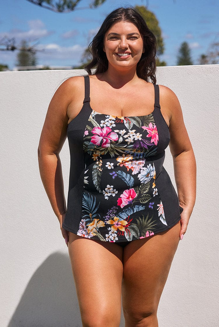Woman wearing a black floral swimsuit against a light background