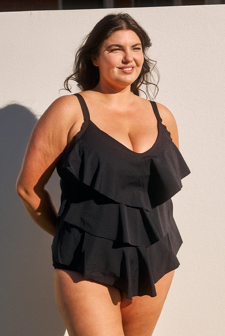 Woman wearing a black ruffled dress against a neutral background