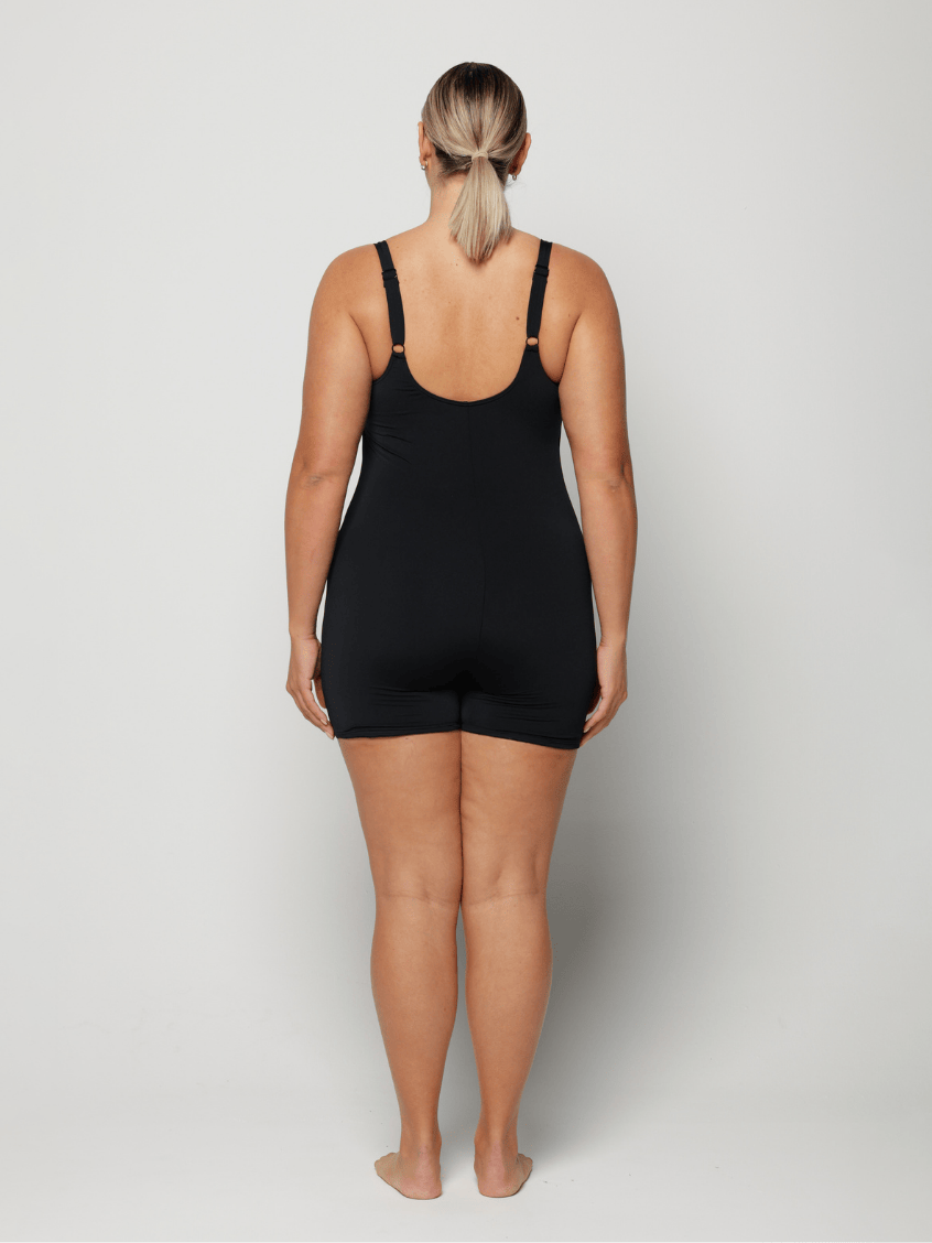 Person wearing a black chlorine resistant boyleg swimsuit on a plain background