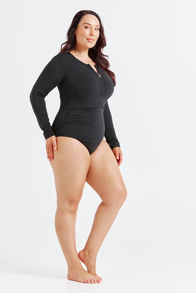 Black chlorine-resistant long sleeve one piece swimsuit with zip front and UPF 50+ sun protection, shown on model standing side on