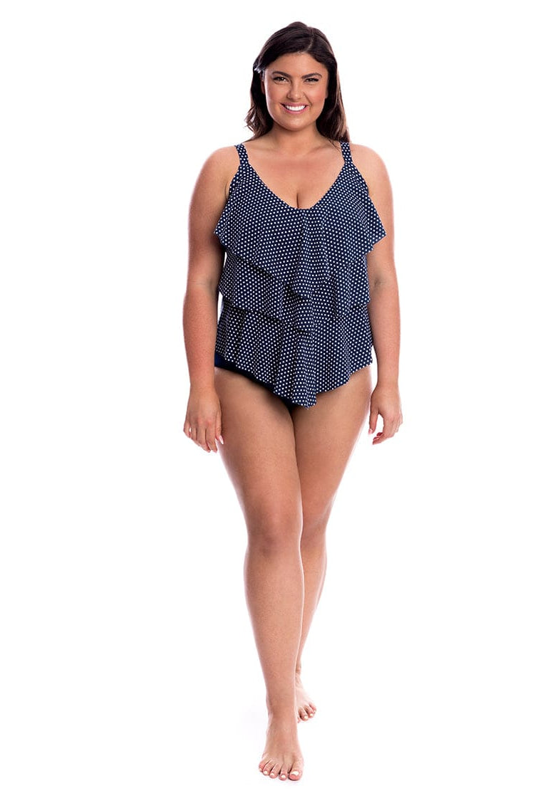 Woman wearing a navy blue polka dot swimsuit on a white background