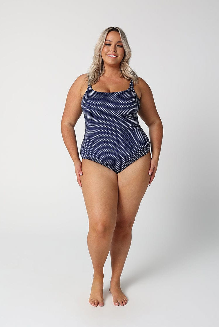 Woman wearing a blue polka dot swimsuit on a white background