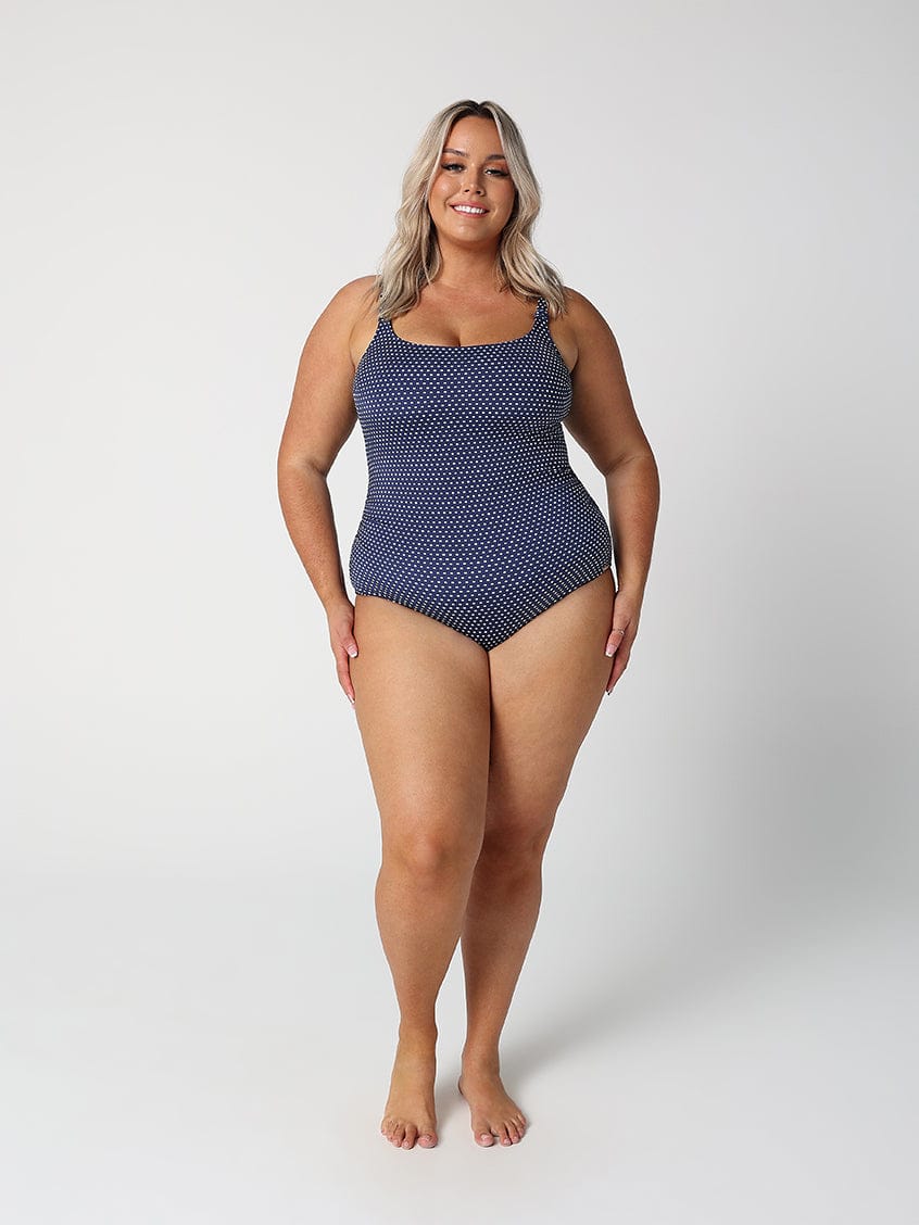 Woman wearing a blue polka dot swimsuit on a white background