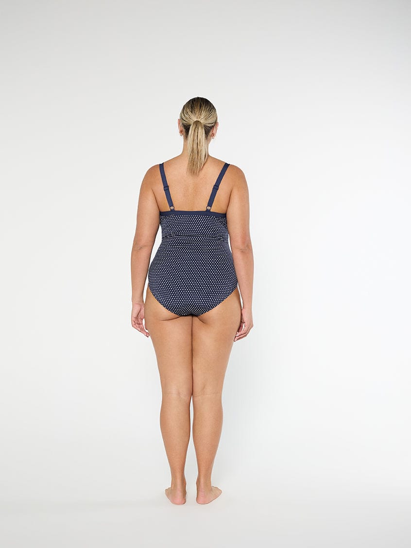 Woman wearing a navy patterned swimsuit on a white background