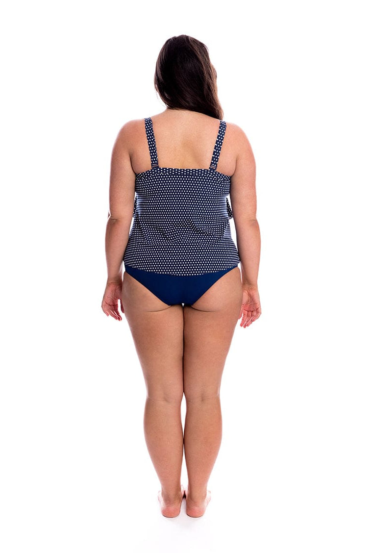 Woman wearing a navy blue polka dot swimsuit on a white background