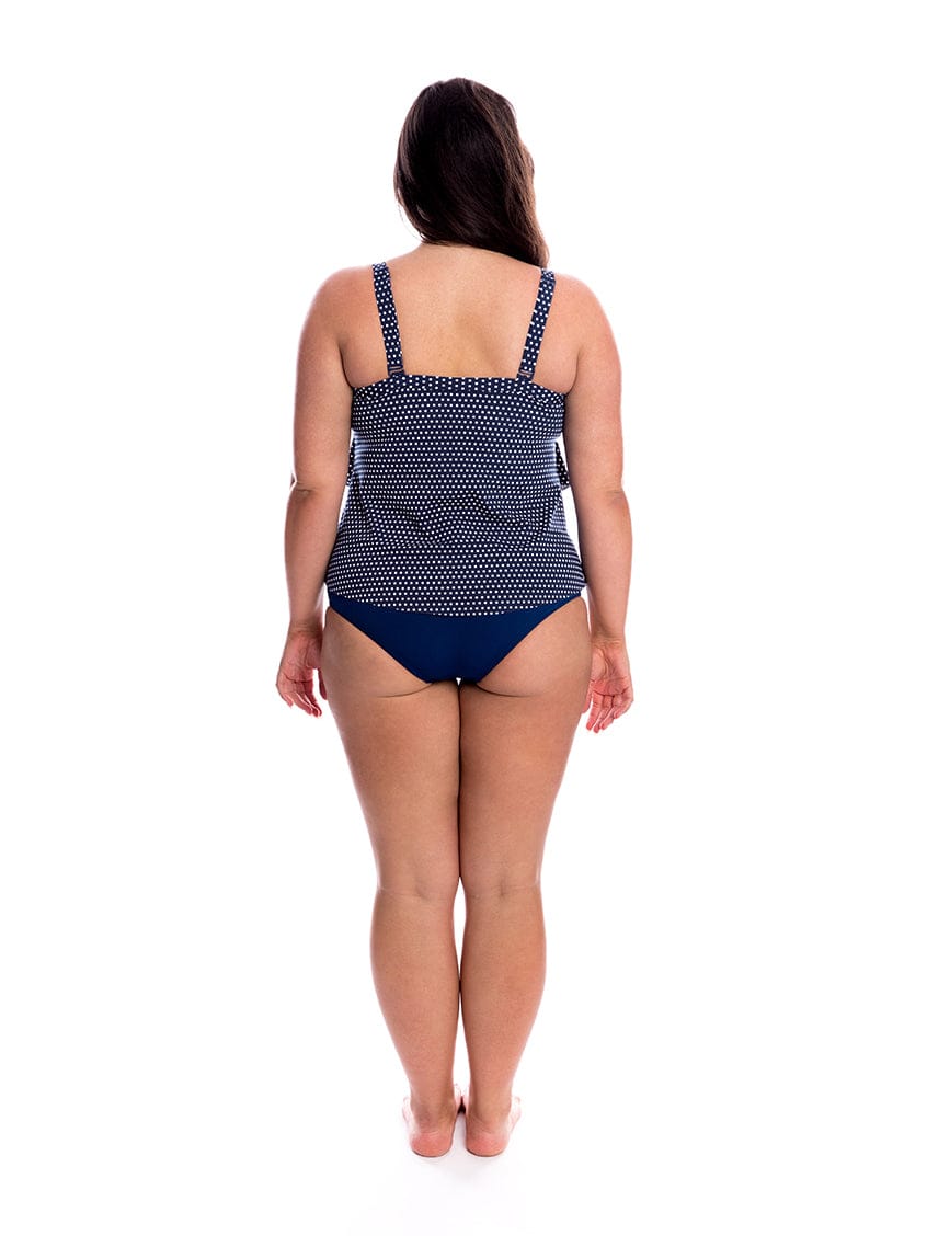 Woman wearing a navy blue polka dot swimsuit on a white background