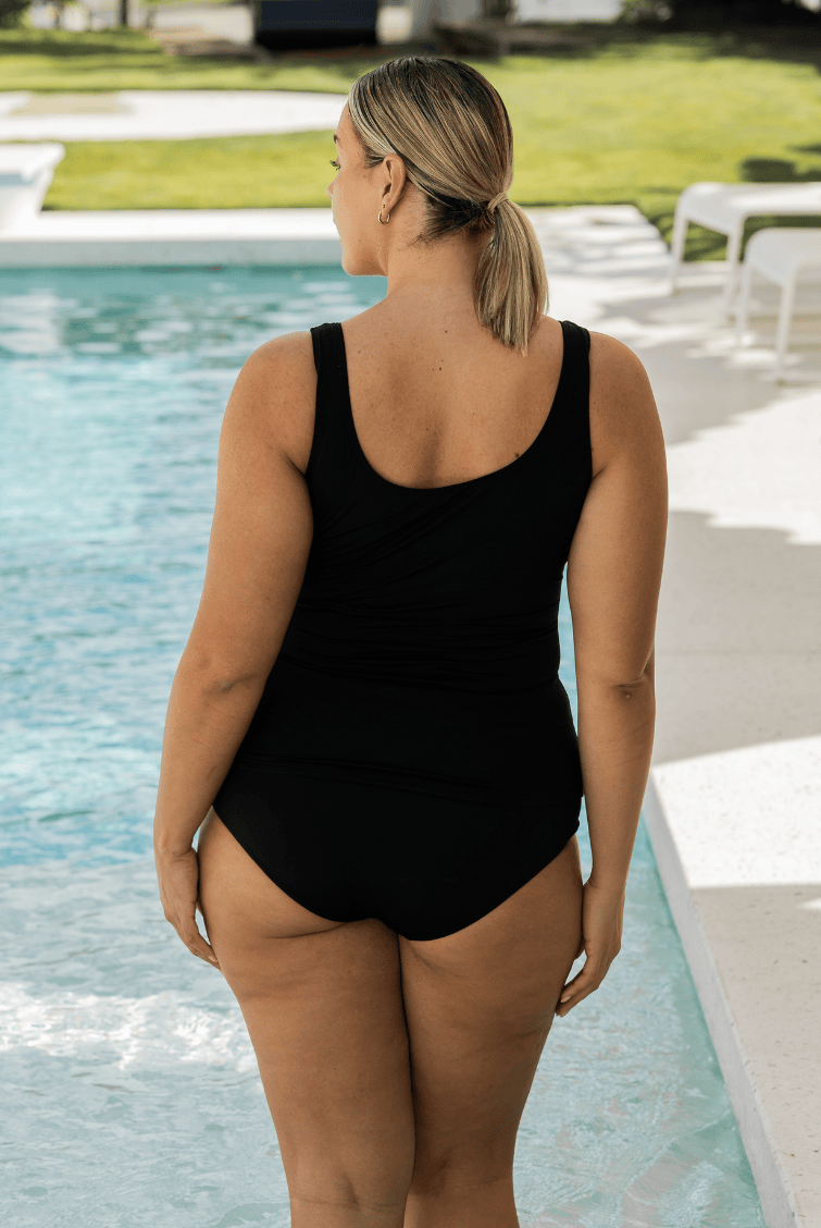 Person wearing a black swimsuit by a pool