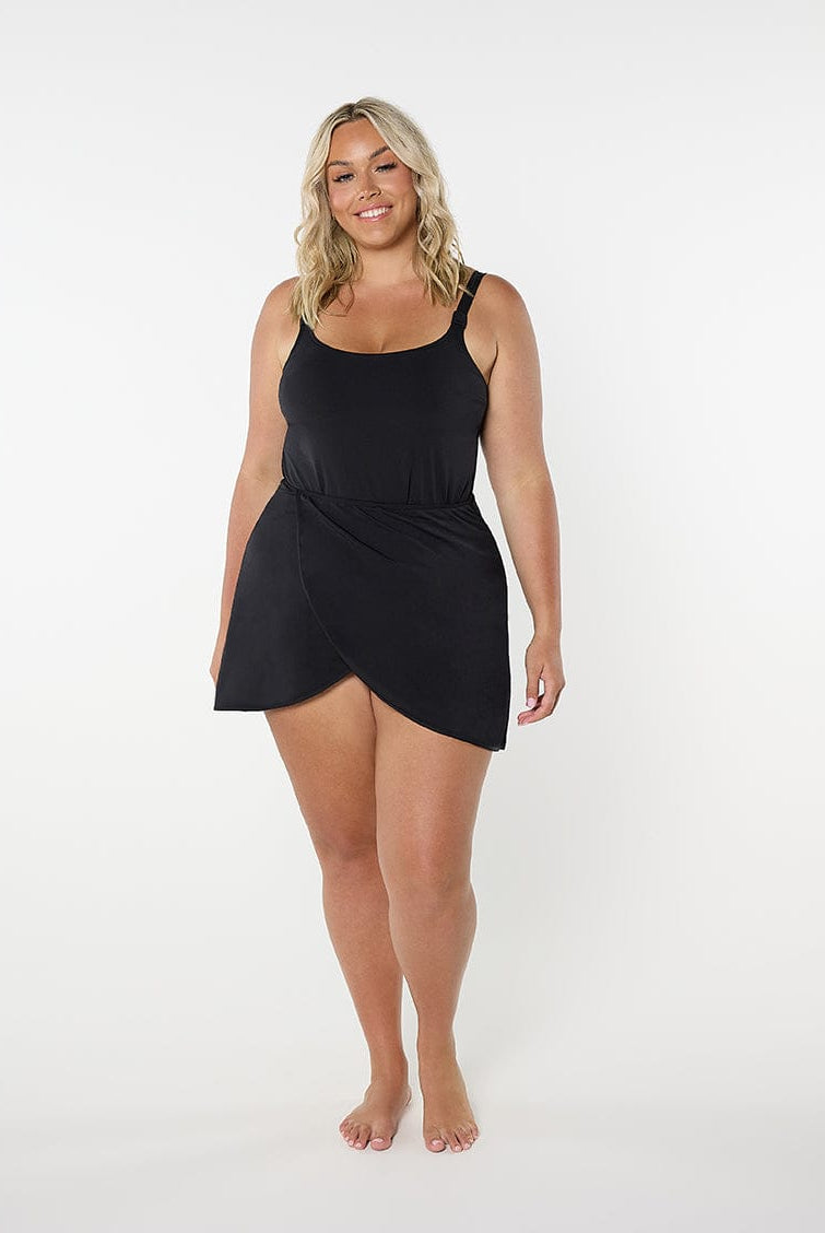 Woman wearing a black swimsuit with a wrap skirt on a white background
