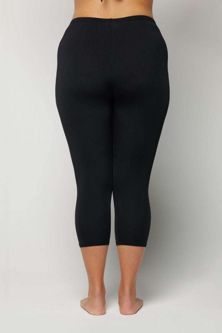 Woman wearing black leggings on a plain background
