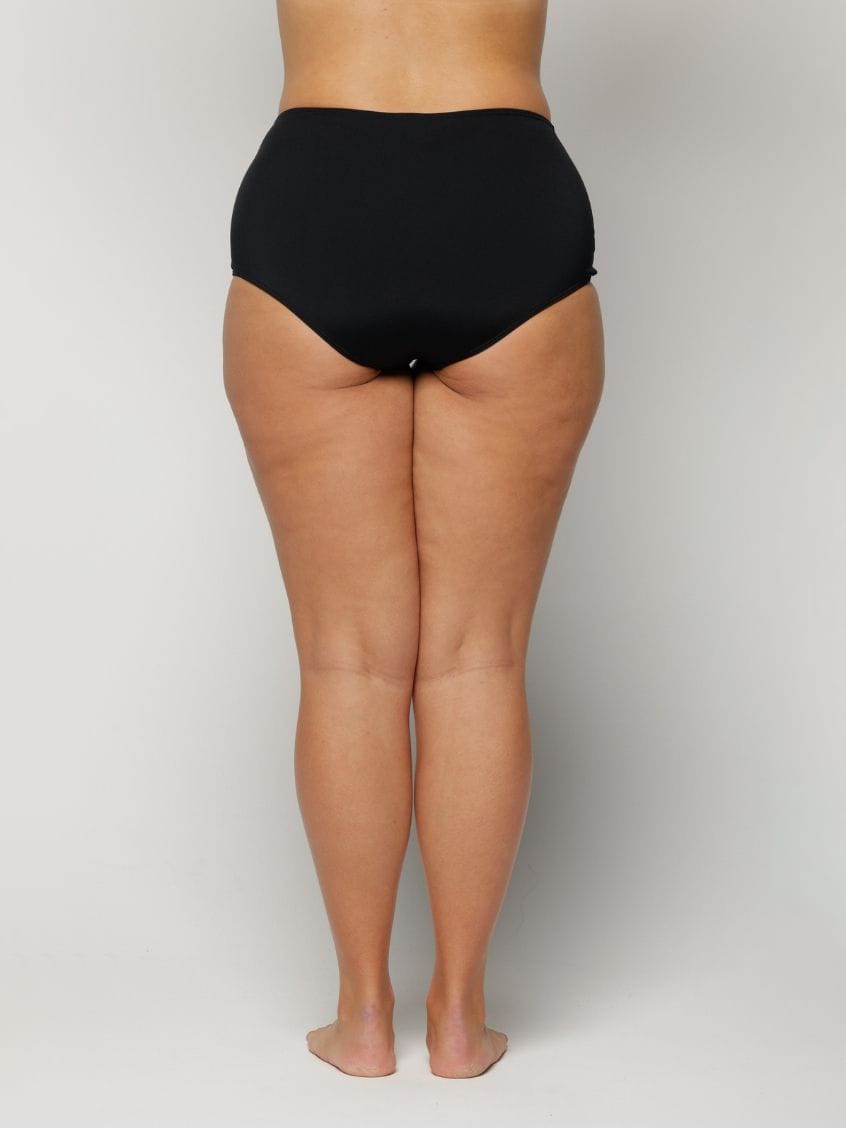 Woman wearing black high-waisted underwear on a plain background