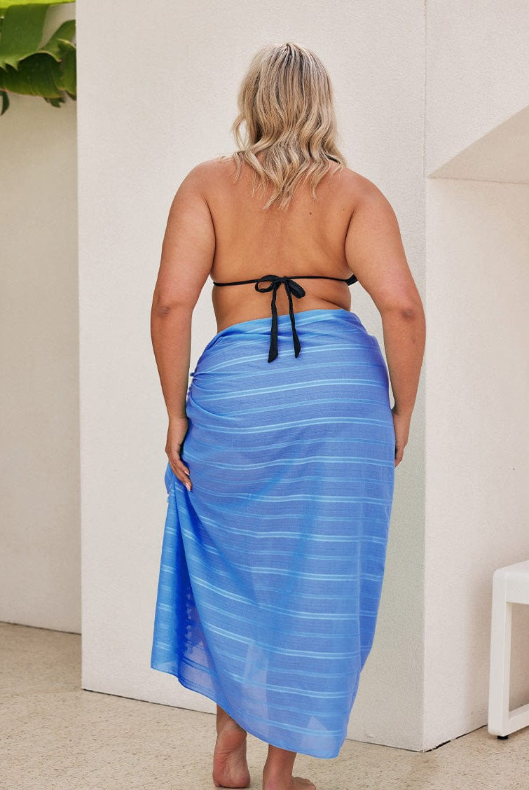 Back of model wearing a long blue sarong with pom pom detail